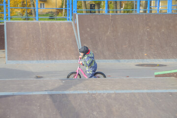 a child, a boy riding a running bike, a bicycle on a sports field, a photo without filters