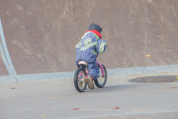 a child, a boy riding a running bike, a bicycle on a sports field, a photo without filters