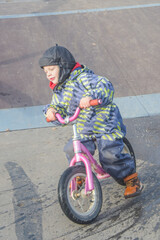 a child, a boy riding a running bike, a bicycle on a sports field, a photo without filters