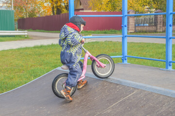 a child, a boy riding a running bike, a bicycle on a sports field, a photo without filters