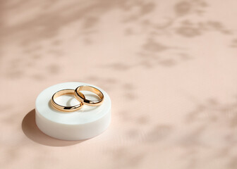 Elegant gold wedding rings displayed on a soft pastel background, showcasing their intricate design in natural light