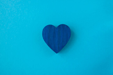 Blue wood heart on the blue fabric background with space for text.