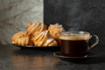 Black coffee in glass cup and cream cakes.