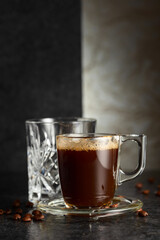 Espresso, glass of cold water, and roasted coffee beans.