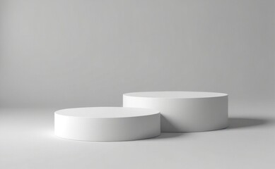 Two simple white cylindrical podiums placed on a gray background for showcasing products or art in a minimalist setting