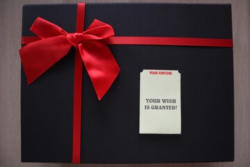 Black gift box with red ribbon, your wish is granted message