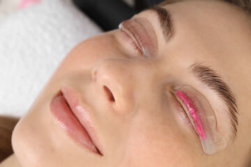 Woman undergoing eyelash laminating procedure in beauty salon, closeup