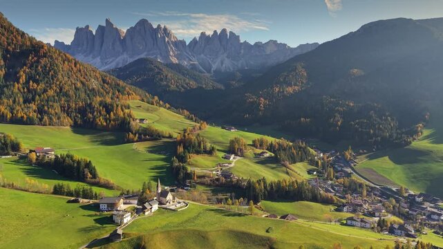 Landscape of Santa Magdalena village in Dolomites, Italy. Lush green fields meet majestic mountains in beautiful autumn setting. Aerial view of Saint Magdalene village