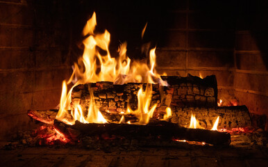 Fireplace burning, wood logs and bright flames. Warm home, heat. Christmas holiday