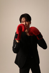 Portrait of self-confident young Asian man with red boxer gloves posing indoor.