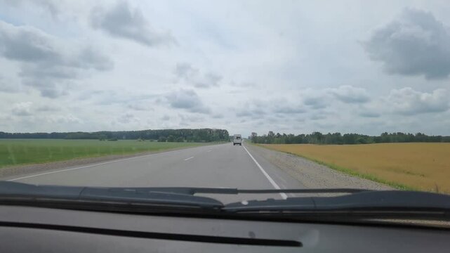 BARNAUL, SIBERIA, ALTAI REGION, RUSSIA - 19 July, 2021: Scenic rural drive through open countryside on a cloudy day capturing passing cars and expansive fields.