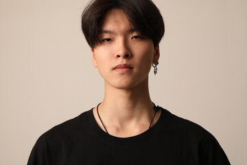 Portrait of confident young Asian man wearing casual black t-shirt posing indoor over white background. 