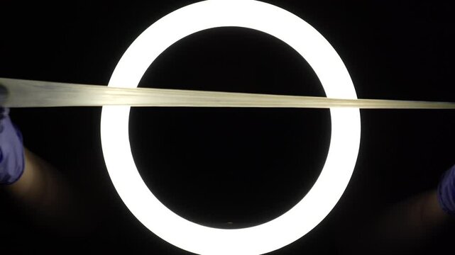 female hands in blue rubber latex gloves open, unfold, stretch and test the strength of a condom close-up on a black background. protection against sexually transmitted diseases and contraception