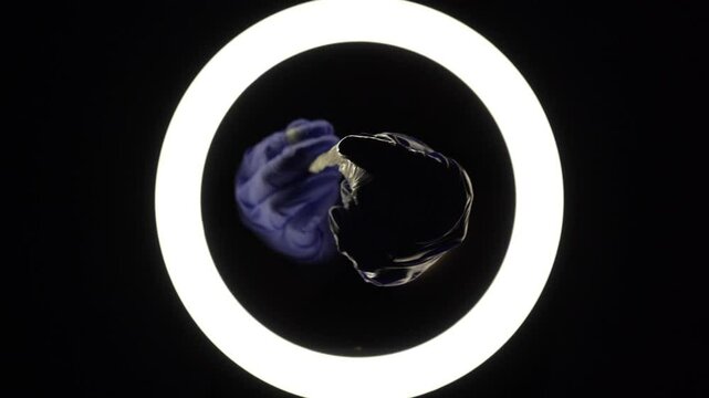 female hands in blue rubber latex gloves open, unfold, stretch and test the strength of a condom close-up on a black background. protection against sexually transmitted diseases and contraception