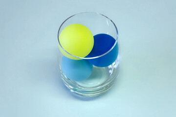 Glass with colored plastic balls instead of water.
Concept of plastic problem in the environment, food and daily life. Ecological and human health problem.