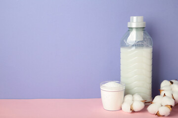 Laundry detergent products with cotton flower on purple background. Space for text