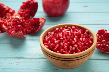 Open pomegranates, and pomegranate seeds in bowl on blue background.