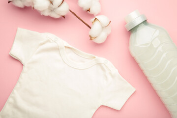 Laundry detergent products with white baby cloth and cotton flower on pink background.