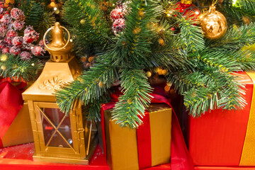 Golden lantern and presents under Christmas tree decorated with ball and red berries