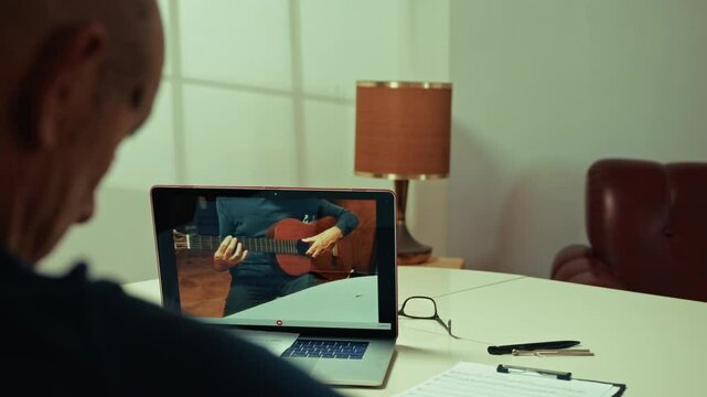 Man Learing How To Plat Guitar On His Laptop