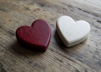 Fototapeta premium Two wooden heart shapes in red and white resting on a rustic wooden surface, symbolizing love and affection in a cozy atmosphere