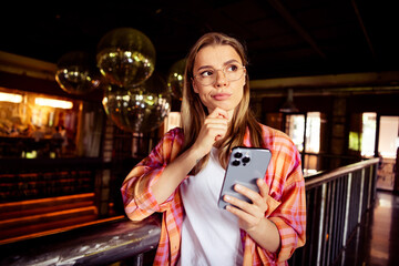 Photo of pretty young blonde girl skeptical think device wear plaid shirt coworking nice comfy dark...