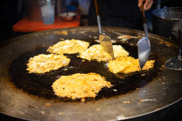 A person is cooking Fried oysters food in a pan that is shaped like a circle. The food is being cooked in oil and he is fried