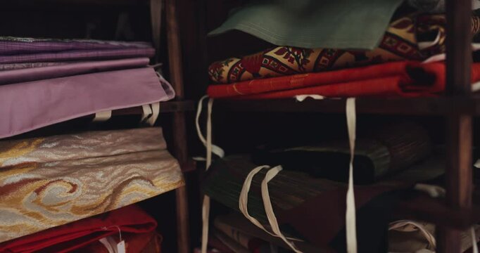 Japan, kimono and traditional fabric shop with silk pattern for obi belt, decorative fashion and closeup. Small business, textile wrap and material on shelves in Tokyo market with cultural designs