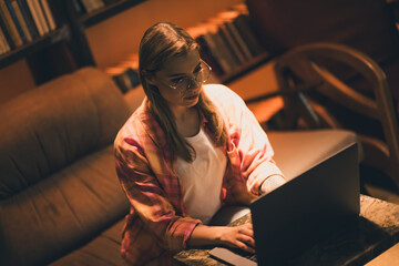 Photo of pretty young blonde girl working netbook wear plaid shirt study dark college library...