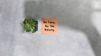 Concept of Be Here, Be You, Belong write on sticky notes isolated on Wooden Table.