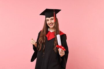 Happy student with diploma after graduation on pink background