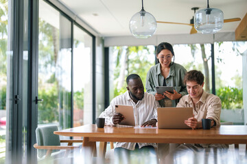 A cheerful team of young adult professionals collaborates efficiently in a contemporary sunlit...