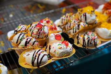 Thai Crispy Pancake. A table with a variety of desserts, including ice cream sandwiches and other treats. The desserts are arranged on a metal rack, and there are several bowls and spoons nearby