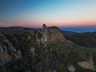 Naklejka premium Ancient fantasy fortress on mountain at sunset - aerial drone view, georgia