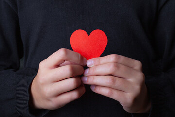 Girl holding a red heart in her hands.