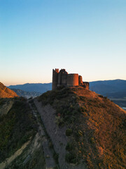 Fototapeta premium Fantasy breathtaking castle on top of mountain at sunset in Georgia Ksani