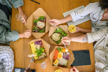 A group of young adult entrepreneurs of various ethnicities share a casual meal, with healthy...