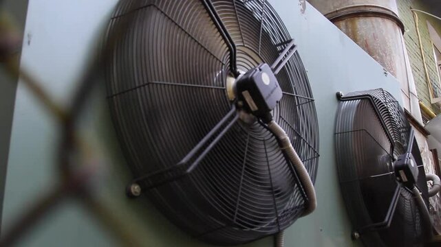 industrial air conditioner extractor fan hanging on the wall outside the building. refrigeration blower running and spinning close up