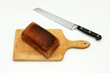 Rye bread loaf on wooden board and knife on a side