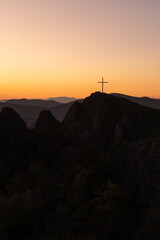 Christian cross on top of a mountain in Georgia against the backdrop of a picturesque fiery sunset