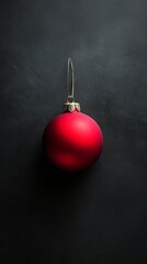 A shiny red Christmas ornament hanging against a dark backdrop during the holiday season