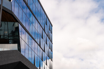 Low angle view of modern office building with glass windows against a blue sky.