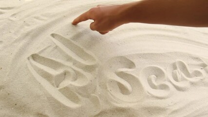 hand draws the inscription "Alboran Sea" on the sand. Sunny coast of the sea and ocean. Symbol of rest and vacations at the resort