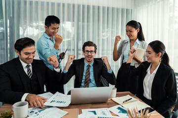 Group of happy businesspeople in celebratory gesture and successful efficient teamwork. Diverse race office worker celebrate after made progress on marketing planning in corporate office. Habiliment