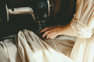 seamstress working with vintage sewing machine on light fabric