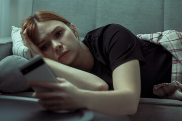 The girl is procrastinating: lying with a phone in her hands, a lazy expression on her face, a concentrated look