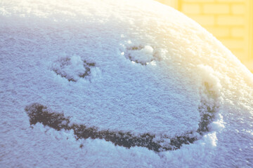 A smile is gently depicted on the snow cover, creating a playful mood and a contrast between cold and warm emotions