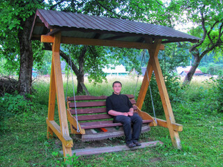 Relaxing on an old wooden swing in a garden