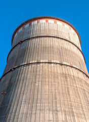 Tall cooling tower against a bright blue sky