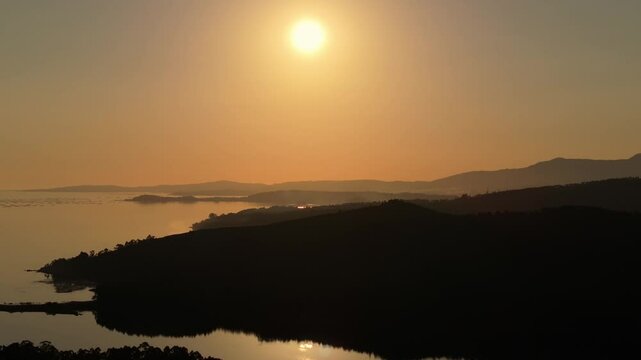 Aerial footage of the silhouette mountains at the coast of Catoira city at sunset in Galicia, Spain